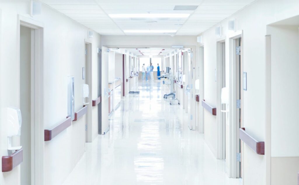 A view of a hospital corridor with medical professionals standing at the far end. InsuranceMD explains The Importance of True Own Specialty Disability Insurance for Physicians.